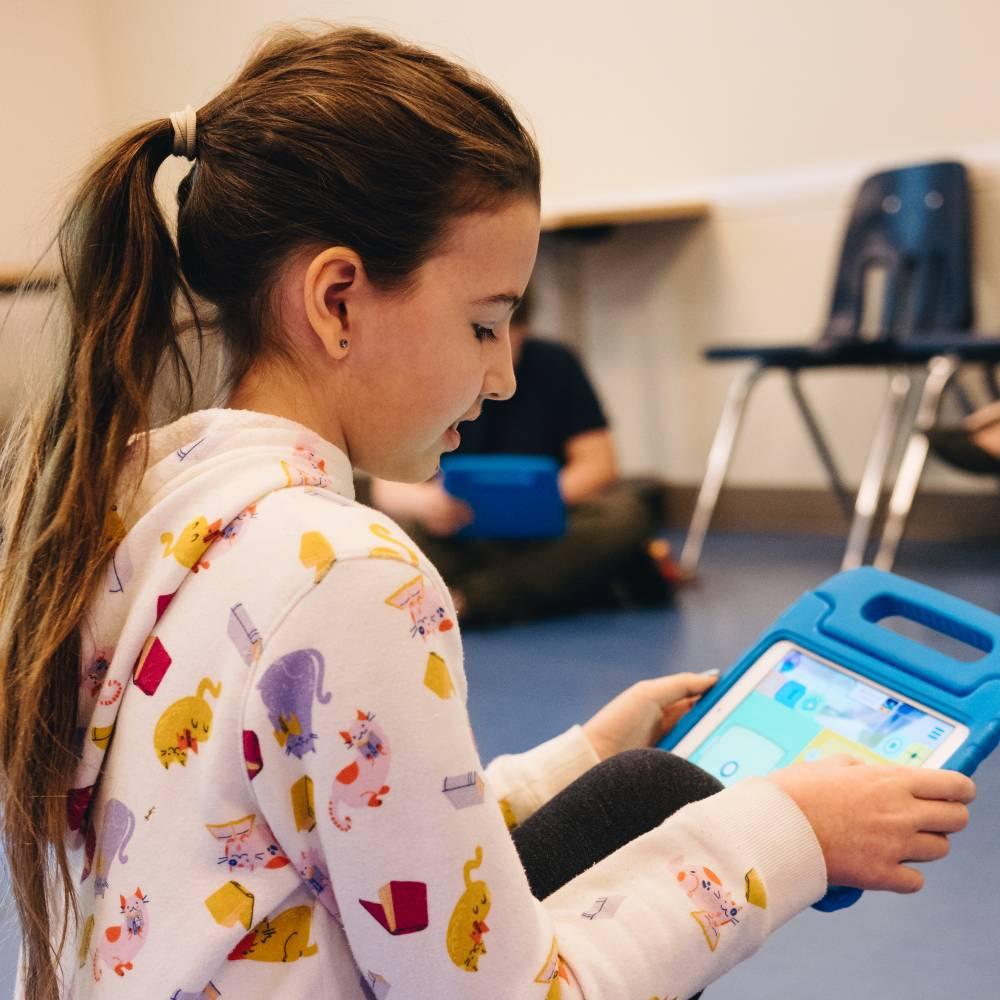 A tween girl uses an iPad during a children's program.