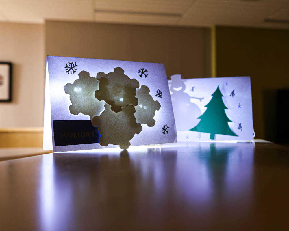 Example of the final light-up cards. One has snowflakes while the other is a snowman with a pine treen.