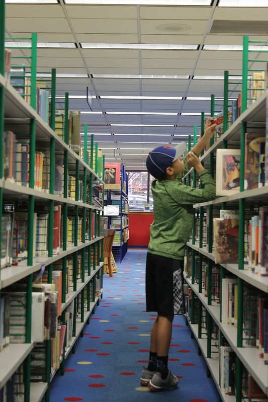 child grabbing book off shelf
