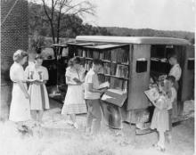 Lois Henze, Bookmobile librarian, assists young patrons.